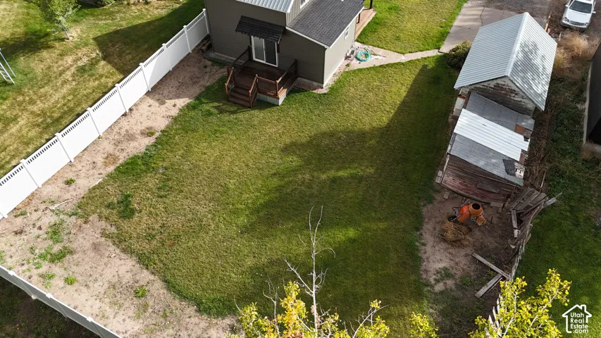 Fenced backyard featuring a wood deck, lawn area, and detached structure