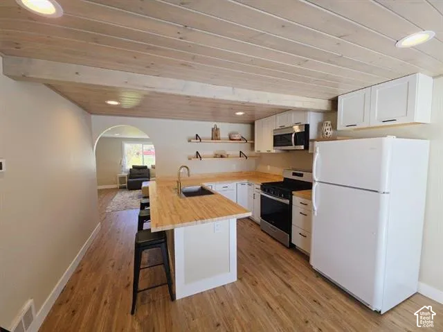 Kitchen featuring wood-finish flooring, white cabinetry, a built-in microwave, and a gas range