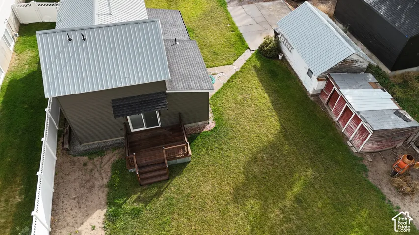Exterior featuring a metal roof, wood-finish deck, white vinyl fencing, and detached storage structures