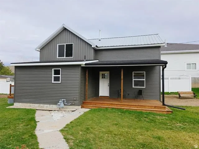 Property exterior featuring dark gray horizontal siding, a light gray metal roof, and a covered wood-finish porch
