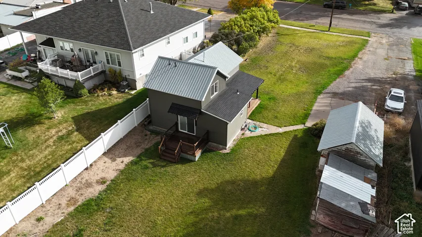 Two-story structure featuring a combination of metal and asphalt shingle roofing, a wooden deck, and a vinyl perimeter fence