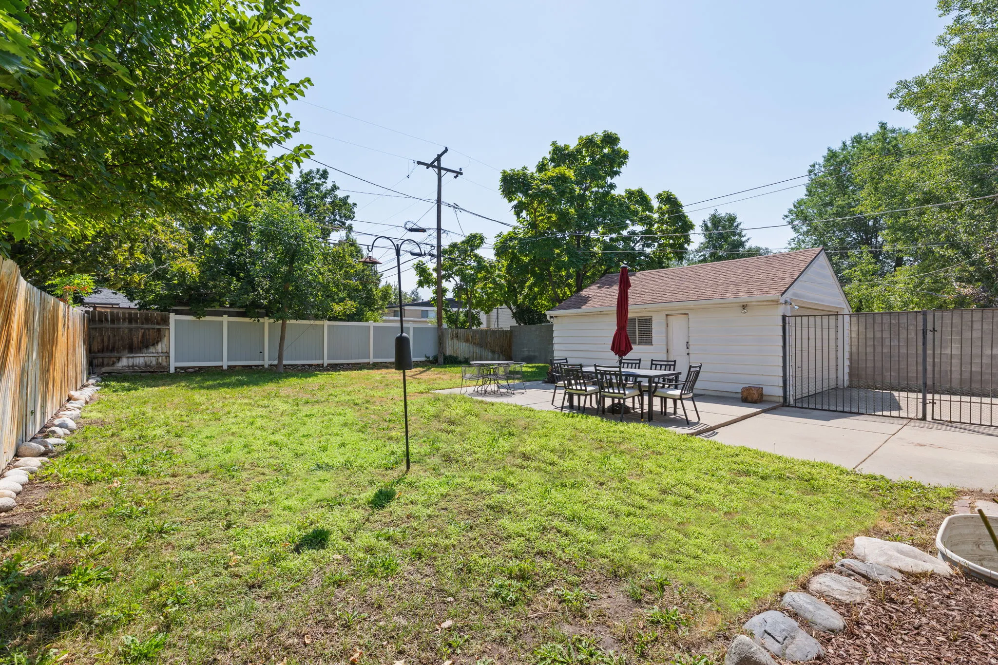 Spacious backyard featuring a manicured lawn, a detached garage, and a concrete patio