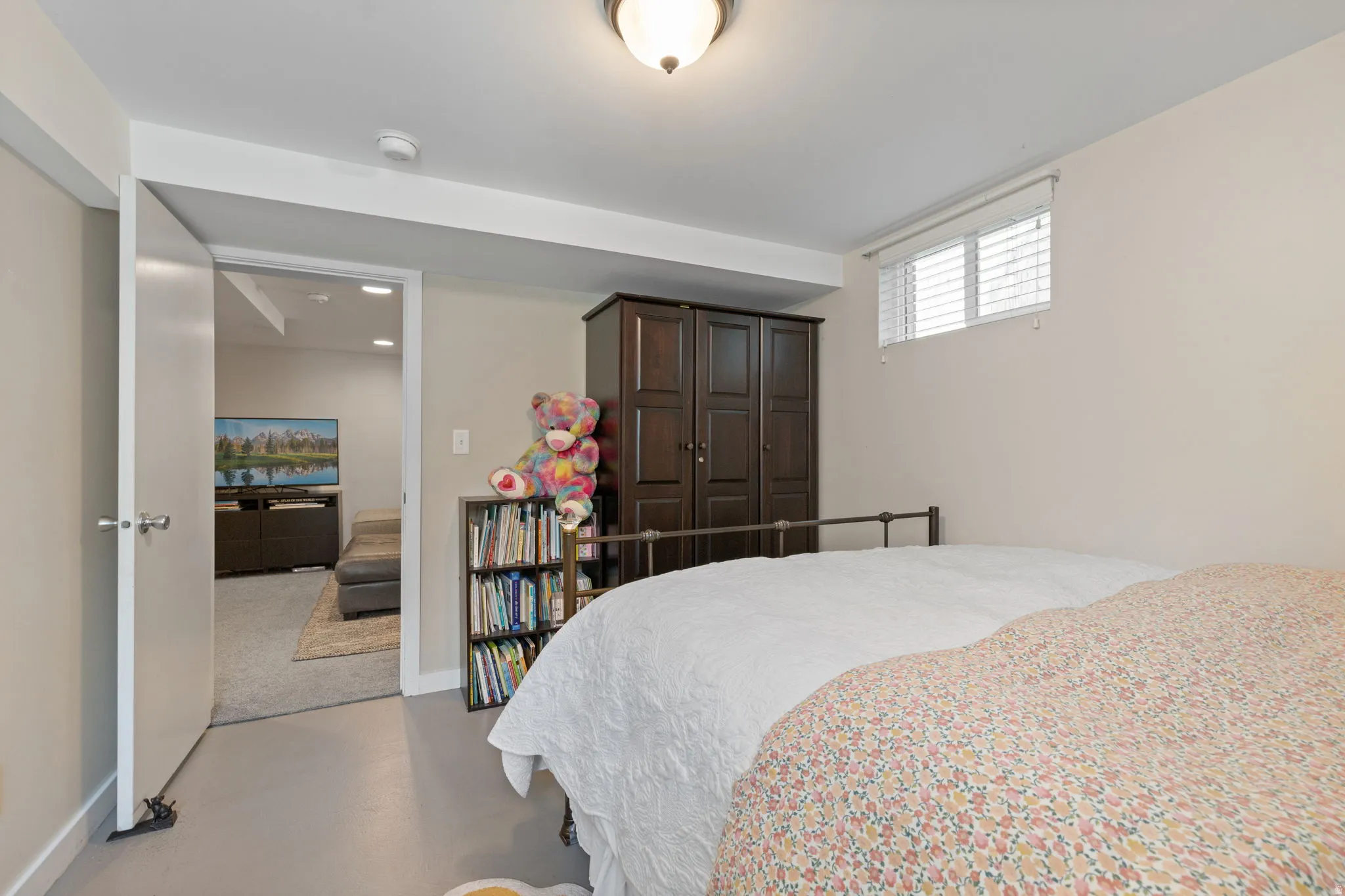 Spacious bedroom featuring a generous bed, neutral wall finishes, and polished concrete flooring