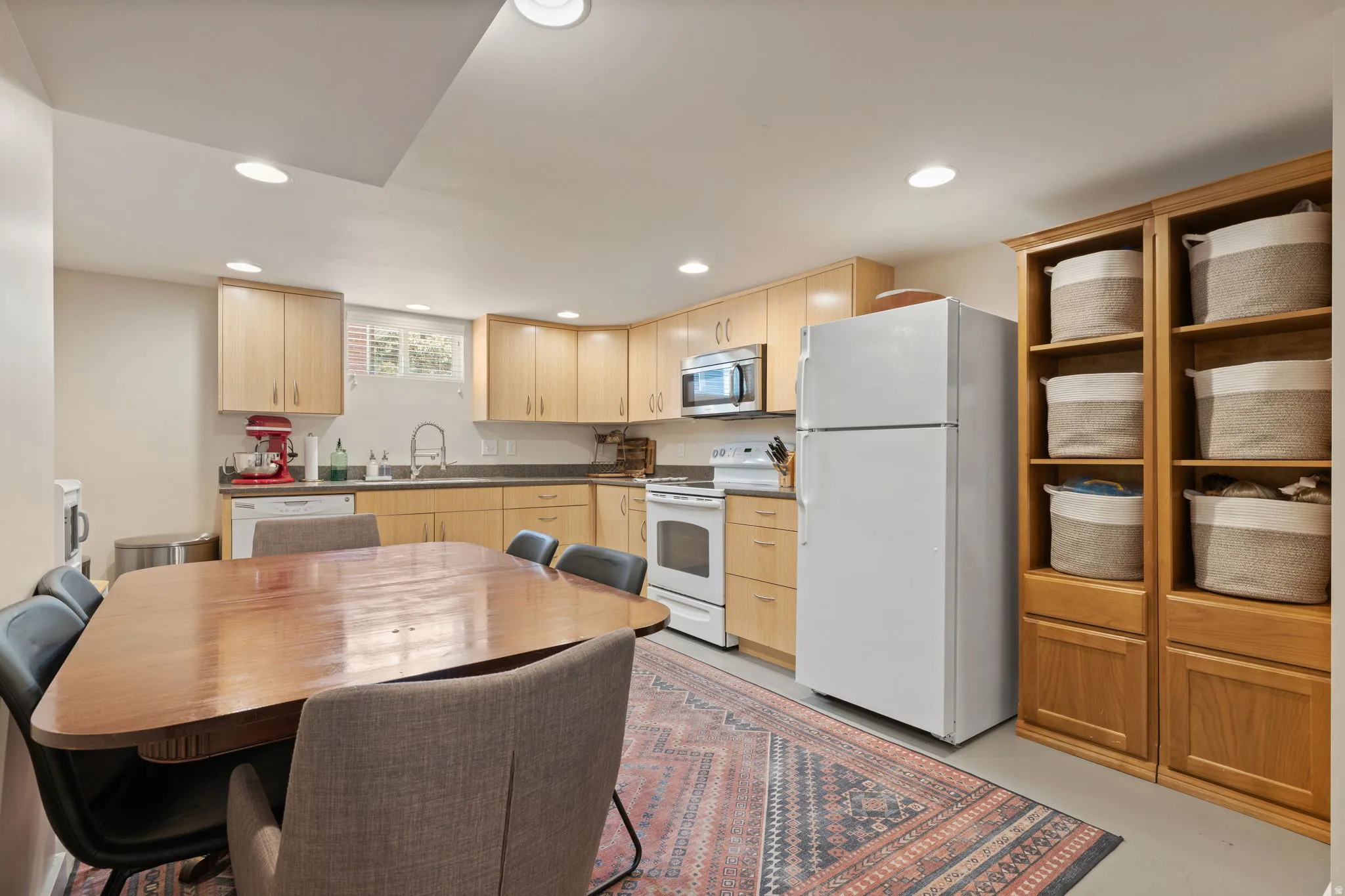 Kitchen featuring light wood cabinetry, white appliances, recessed lighting, and a window above the sink