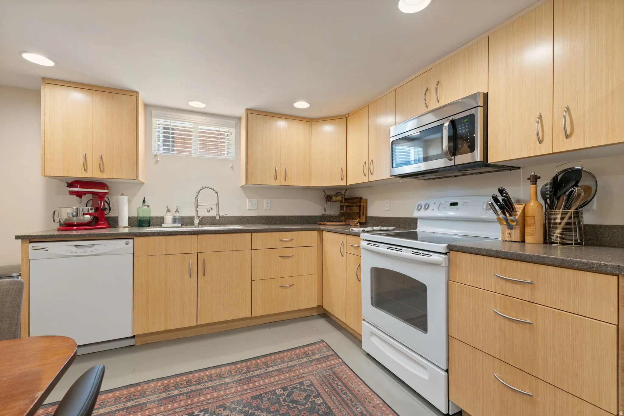 Kitchen featuring light wood-finish cabinetry, dark countertops, and a stainless steel microwave