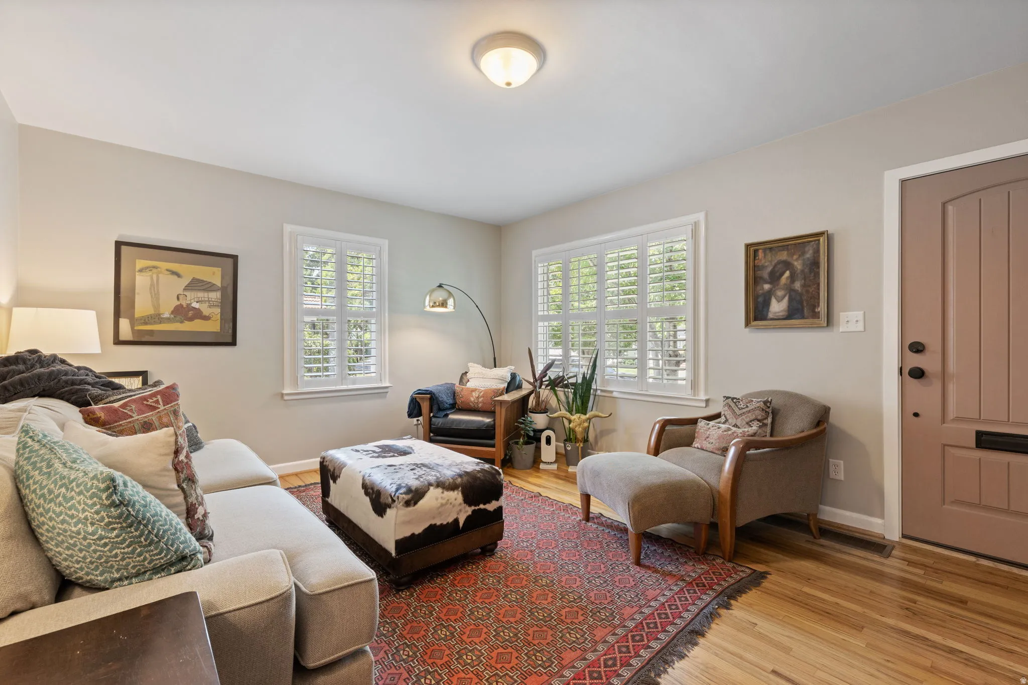 Living area featuring wood-finish flooring, white plantation shutters, a neutral paint palette, and a paneled entry door