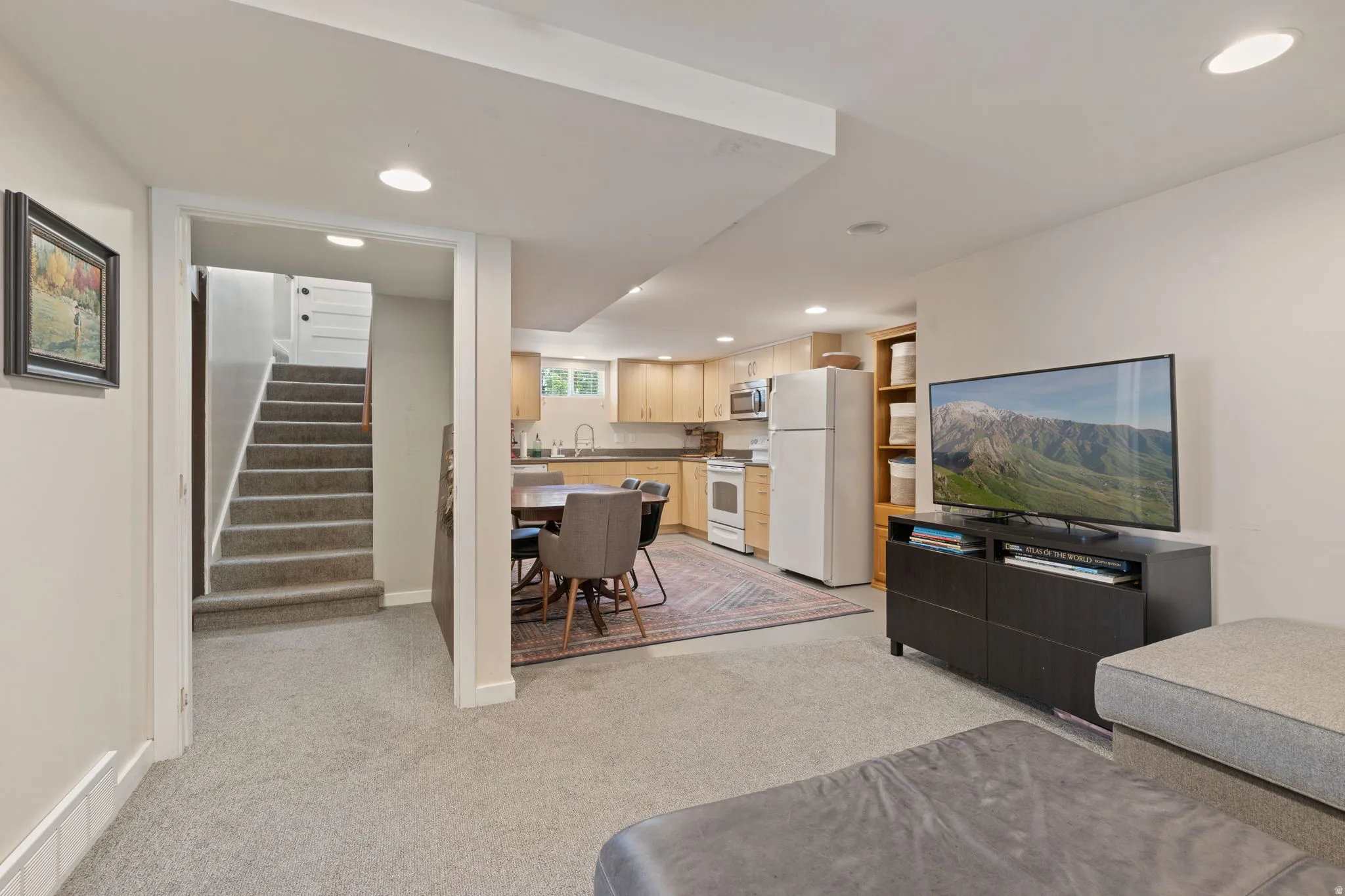 Carpeted living area with recessed lighting, featuring an open-concept layout to a full kitchen