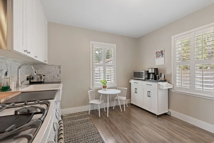 Kitchen featuring wood-finish flooring, white cabinetry, a built-in sink, and white window shutters