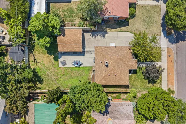 Aerial view showcasing a multi-structure property with mature landscaping, including established trees throughout the grounds