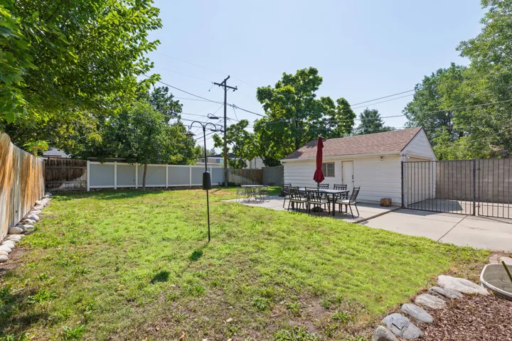Spacious backyard featuring a manicured lawn, a detached garage, and a concrete patio