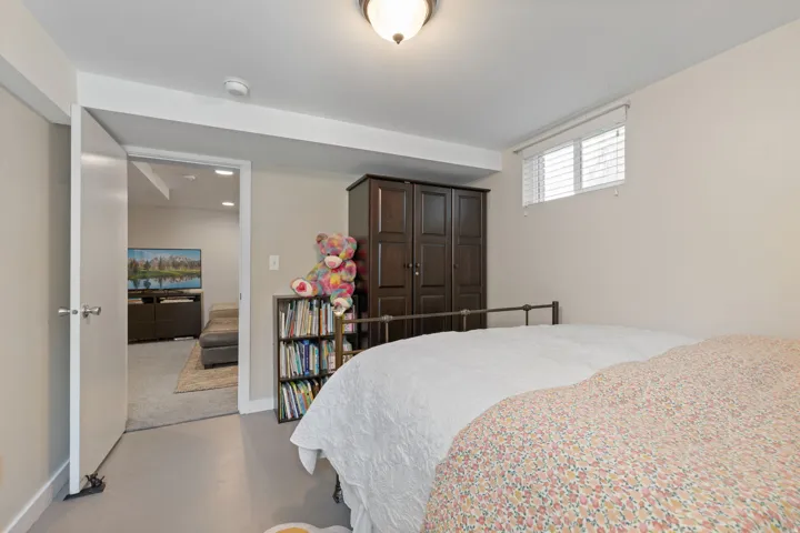 Spacious bedroom featuring a generous bed, neutral wall finishes, and polished concrete flooring