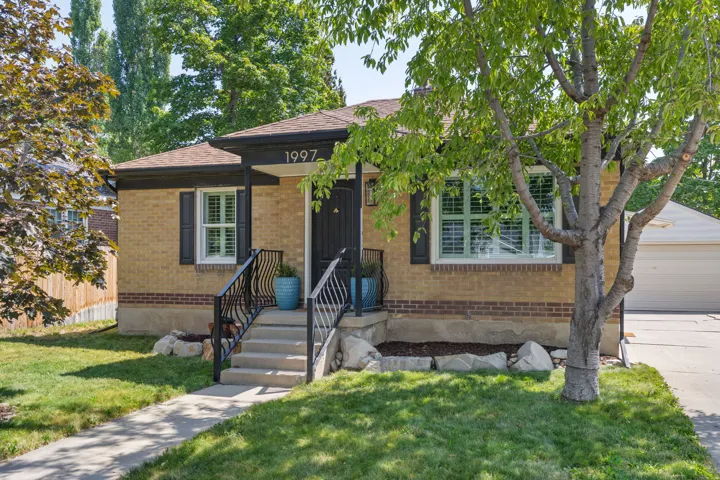 Charming brick home featuring a welcoming front elevation with black accent trim and substantial entry stairs