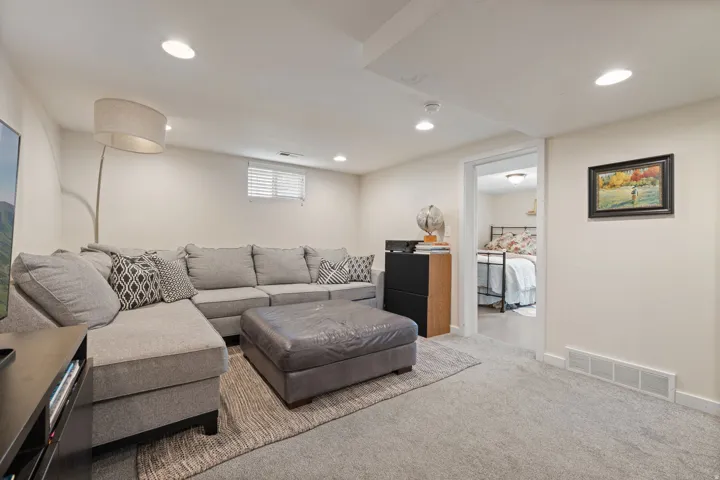 Carpeted living space with recessed lighting and a window with blinds