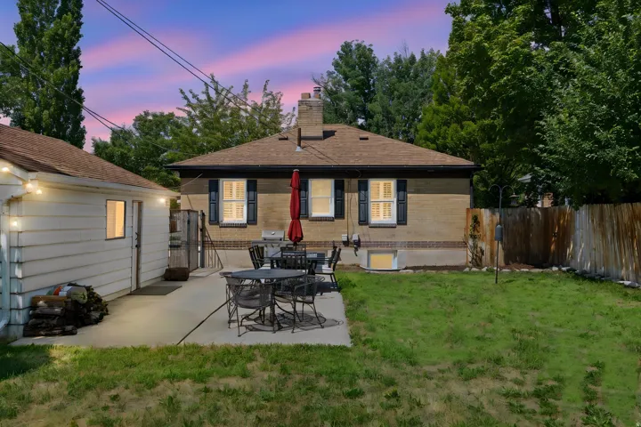 Brick exterior with dark shutters, gabled roof, and a privacy fence