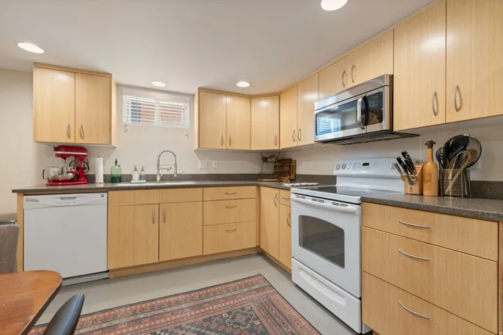 Kitchen featuring light wood-finish cabinetry, dark countertops, and a stainless steel microwave