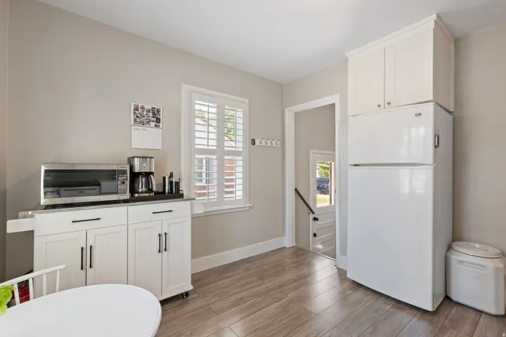 Bright interior space featuring a window with white plantation shutters, light gray wall paint, and wood-finish flooring