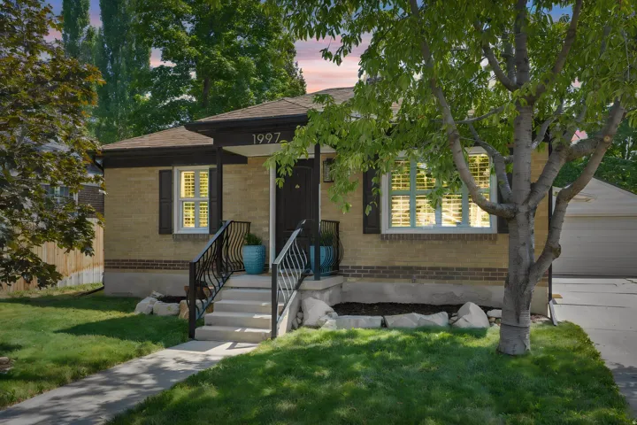 Brick exterior with a covered entry, concrete steps, and decorative iron railings