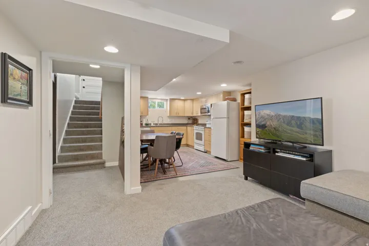 Carpeted living area with recessed lighting, featuring an open-concept layout to a full kitchen