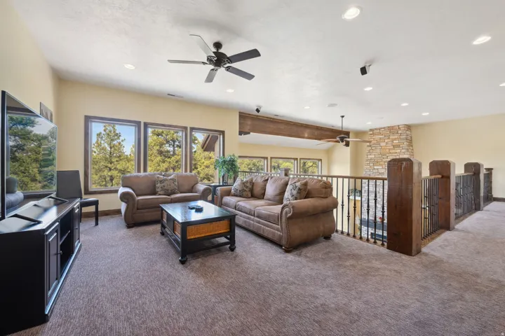 Spacious upper-level recreation room featuring abundant natural light from multiple large windows, recessed ceiling lighting, ceiling fan, and plush carpet flooring