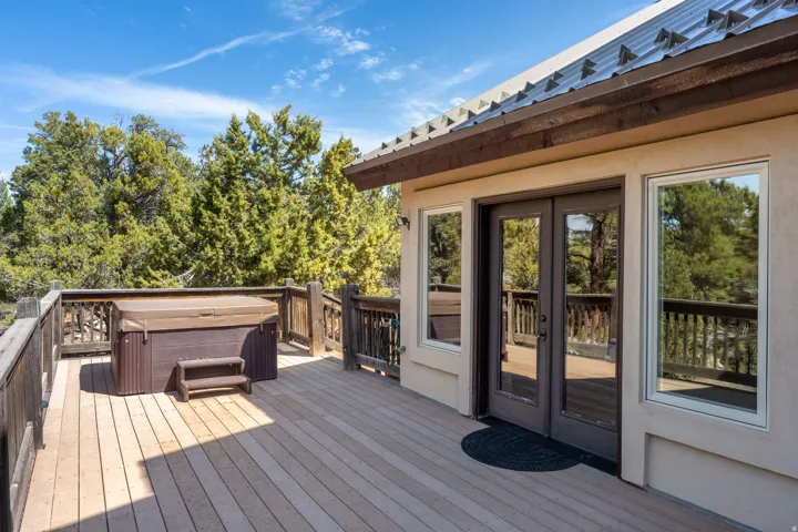 Expansive exterior deck featuring a hot tub, wood railings, and a solid exterior wall