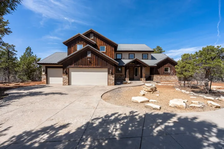 Craftsman-style exterior featuring a multi-gable metal roof, horizontal wood siding, and stacked stone accents