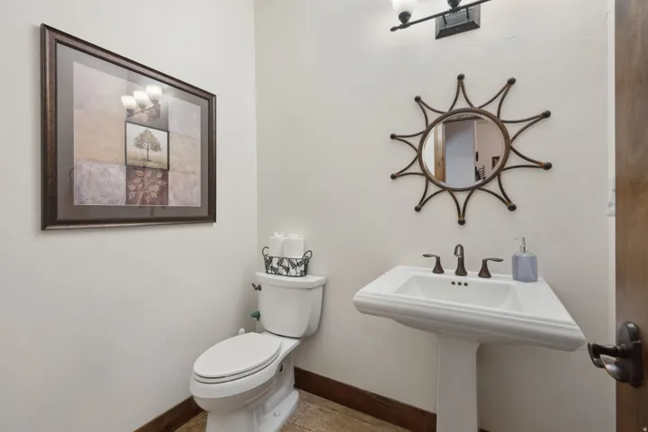 Pedestal sink with oil-rubbed bronze fixtures, a decorative mirror, and a wall-mounted vanity light