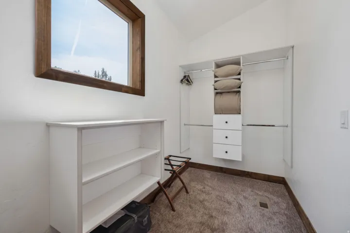 Spacious walk-in closet featuring custom built-in cabinetry with dual sliding doors, open shelving for folded garments, and dedicated drawer storage