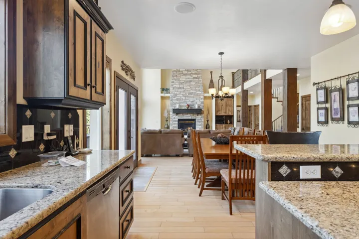 Kitchen featuring granite countertops, wood cabinetry with dark hardware, a stainless steel sink, and an integrated dishwasher