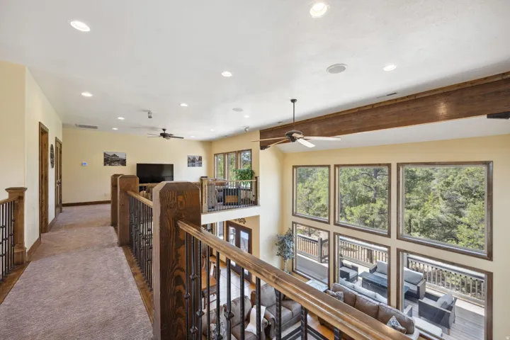 Upper-level hallway featuring warm yellow walls, recessed lighting, and a wooden railing with spindle detailing