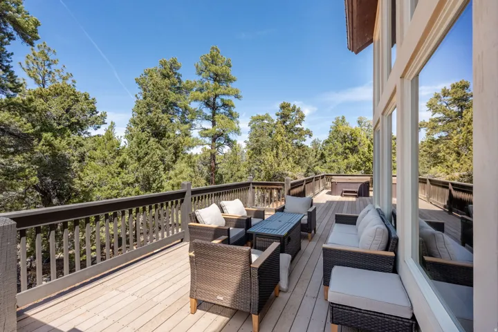 Expansive wood-finish deck featuring a full-height railing system, outdoor spa, and large multi-pane windows providing natural light