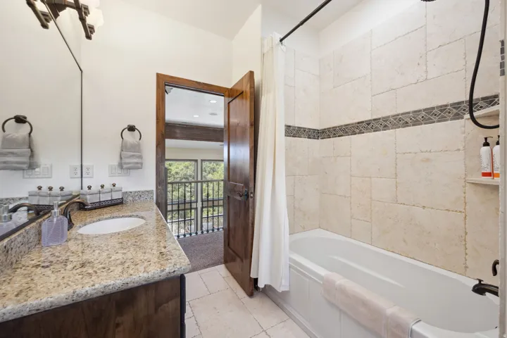 Bathroom featuring a single vanity with a granite countertop and an undermount sink