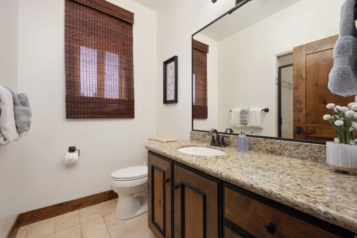 Elegant master bathroom showcasing a granite countertop vanity with dual-sink configuration, dark wood cabinetry with decorative hardware, and oil-rubbed bronze faucet fixtures