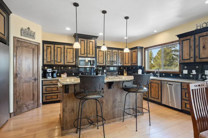 Chef's kitchen showcasing custom wood cabinetry with bronze hardware, stainless steel appliances, and a dual-island layout with breakfast bar seating