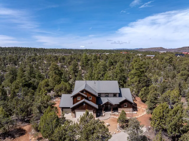Expansive property featuring a multi-level residence with a metal roof, wood siding, and stone accents
