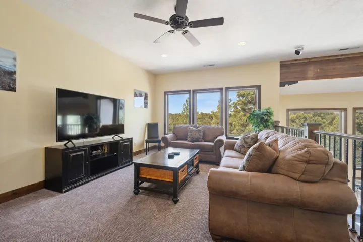 Spacious loft area featuring a ceiling fan with light, recessed lighting, and track lighting