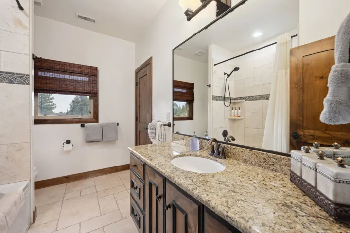 Spa-inspired primary bathroom featuring a dual-sink vanity with granite countertop, bronze hardware, and ample storage