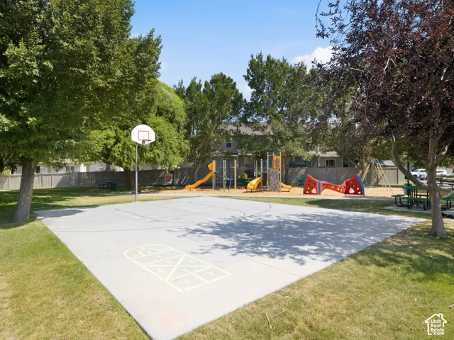 Recreational outdoor space featuring a dedicated sports court with court markings, basketball hoop, and modern playground equipment including slides and climbing structures