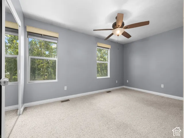 Room with light gray walls, two windows with blinds, and light-colored carpet