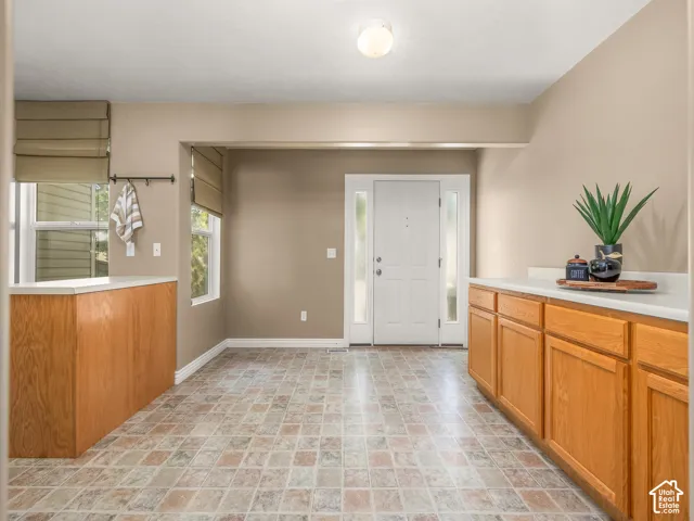 Welcoming entryway showcasing ceramic tile flooring in a warm geometric pattern, rich wood-finish cabinetry with ample storage, recessed ceiling lighting, and a bright entry door with sidelights