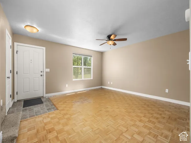 Spacious main living area featuring parquet wood-finish flooring, neutral taupe walls, and abundant natural light from large windows