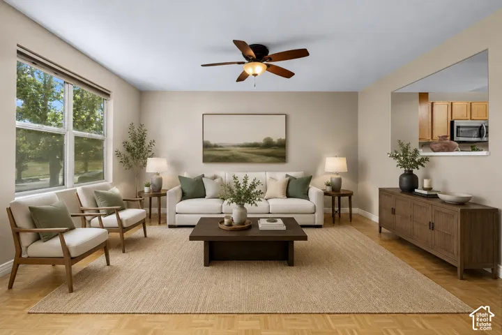 Spacious living area featuring wood-finish flooring, a ceiling fan, and large windows