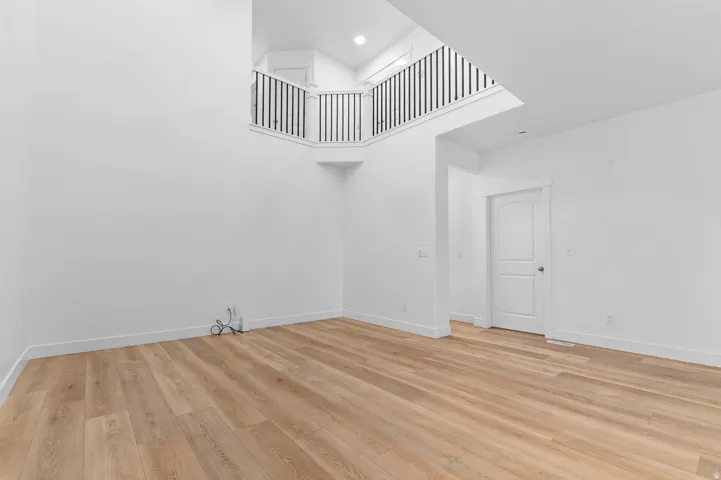 Spacious room featuring wood-finish flooring, white baseboards, and bright white walls