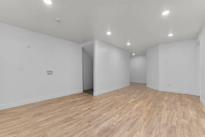 Spacious open floor plan with recessed ceiling lighting, pristine white drywall, and warm wood-finish flooring throughout