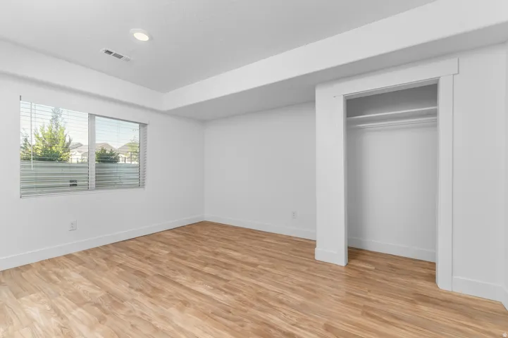 Room featuring wood-finish flooring, recessed lighting, and a window with horizontal blinds