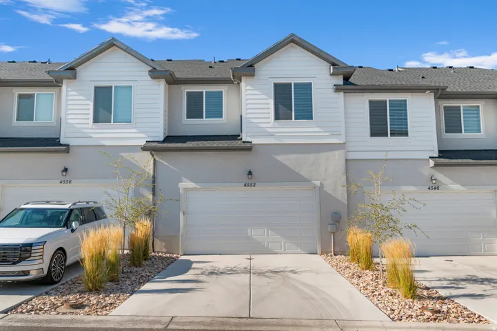 Townhome exterior featuring light gray stucco and white horizontal siding