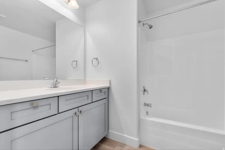Modern bathroom featuring a light gray vanity with square hardware, a white countertop, and a built-in sink