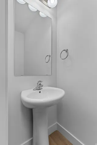 Pedestal sink with chrome faucet, large vanity mirror, and three-bulb vanity lighting