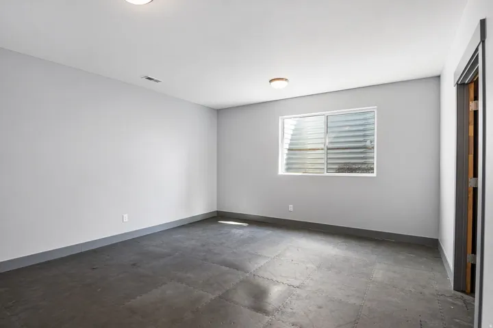 Spacious room showcasing polished concrete flooring, neutral wall finishes, and abundant natural light from a large multi-pane window