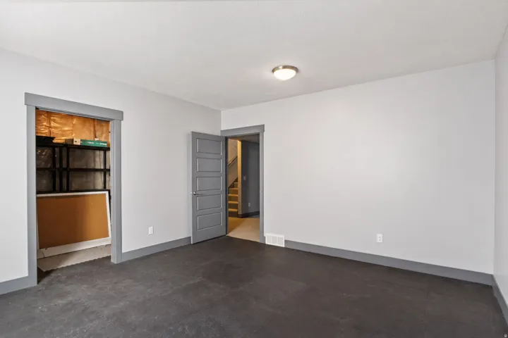 Spacious room featuring gray walls, dark flooring, and a flush-mount ceiling light