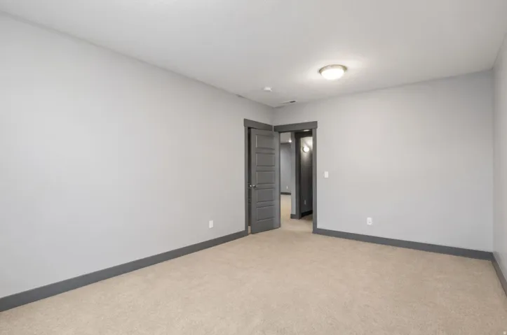 Spacious room featuring neutral wall finishes, carpeted flooring, recessed ceiling lighting, and double-door closet entry with dark frame detailing